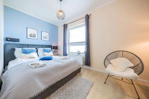 um quarto com uma cama, uma cadeira e uma janela em Pomorskie Apartamenty - Apartment Sea View em Gdansk