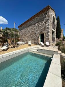uma piscina em frente a um edifício de pedra em Mas Saint-Ferdinand - maison avec piscine em La Capelle-et-Masmolène