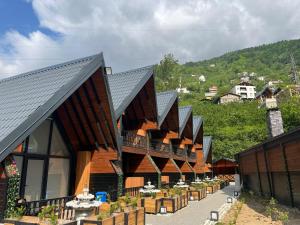 a row of wooden buildings with a mountain in the background at Aquarium BUNGALOW UZUNGÖL in Uzungöl