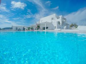 a swimming pool with blue water in front of a white building at The Fisherman's House Santorini in Akrotiri