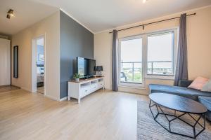 uma sala de estar com um sofá azul e uma televisão em Pomorskie Apartamenty - Apartment Sea View em Gdansk