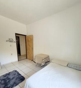 a white bedroom with a bed and a door at Quarto Proença in Campinas