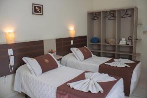 a hotel room with two beds with towels on them at Hotel do Reinildo I in Cachoeira Paulista