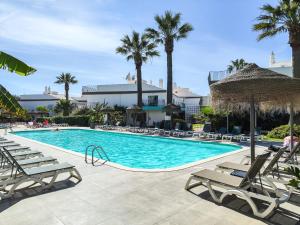a swimming pool with lounge chairs and palm trees at Bayside Salgados in Albufeira
