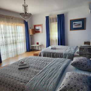 2 camas en un dormitorio con cortinas azules en Don Sidónio Alojamentos en Portimão