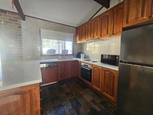 uma cozinha com armários de madeira e um frigorífico preto em Entire 3 bedroom personal house in Chipping Norton em Chipping Norton