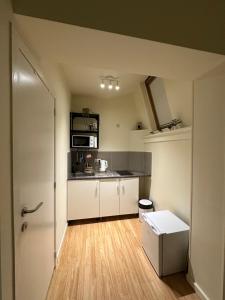 una pequeña cocina con armarios blancos y nevera. en Wonder home, en Bruselas
