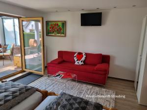 a living room with a red couch with a heart pillow at Privatunterkunft Straubing in Straubing