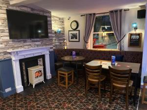 a restaurant with a fireplace and two tables and a tv at Ye Olde Vaults in Ashbourne