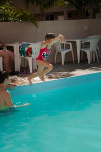 a woman in a bikini jumping into a swimming pool at Marechal Plaza Hotel in São Gabriel
