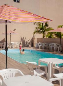 a person swimming in a swimming pool with an umbrella at Marechal Plaza Hotel in São Gabriel