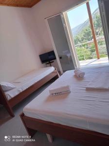 two beds in a room with a large window at Guest House Emiljos Flamur in Berat