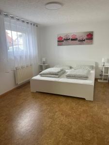 a white bedroom with two beds and a window at Fewo Haus Ema in Lahr