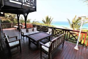 a wooden deck with a table and chairs and the ocean at Casa 26 Graus in Ponta do Ouro