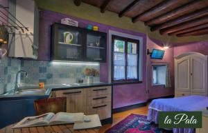 a kitchen with purple walls and a table with books at Il Borghetto Vacanze nei Mulini in Valeggio sul Mincio
