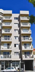 a tall white building with cars parked in front of it at Baleine in Puerto Madryn
