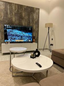 Smart luxury apartment 3bedrooms في الرياض: غرفة معيشة مع طاولة وتلفزيون