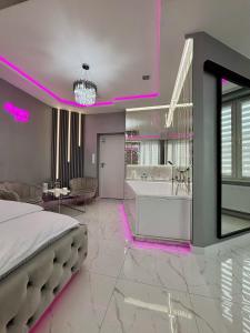a bedroom with a bed and a bathroom with pink lights at Apartament "Prezydencki Deluxe" Centrum z dużą wanną dla Dwojga in Gniezno +7 photos
