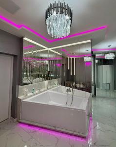 a large white tub in a room with purple lighting at Apartament "Prezydencki Deluxe" Centrum z dużą wanną dla Dwojga in Gniezno
