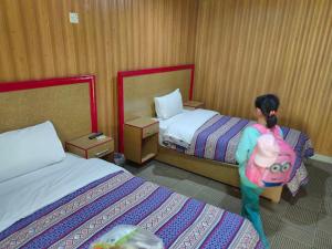 - une petite fille qui marche entre deux lits dans une chambre d'hôtel dans l'établissement Canopy Nexus Resort Over The River, à Gilgit