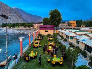 a group of people sitting at tables near a river at Canopy Nexus Resort Over The River in Gilgit