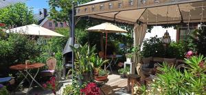 un patio con mesas, plantas y una sombrilla en B&B Fischerstüble - adults only, en Hagnau