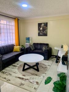 uma sala de estar com um sofá e uma mesa em Trice Homes One Bedroom Condo at Lavender Apartment em Nanyuki