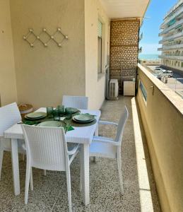 uma mesa de jantar branca e cadeiras numa varanda em Appartamento luminoso vista mare em Lido di Jesolo