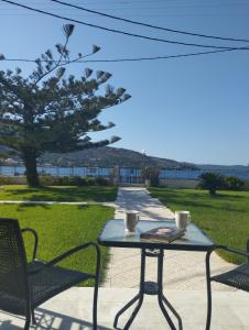 a table with two cups and a book and two chairs at Kalamionas Studios & Apartments in Kassiopi