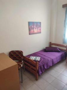 a bedroom with a purple bed and a chair at Beautiful apartment ANAIS near the sea in Agia Triada