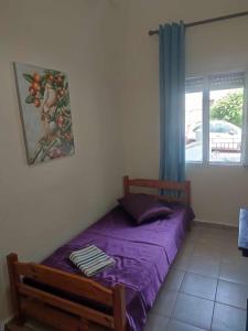 1 dormitorio con cama morada y ventana en Beautiful apartment ANAIS near the sea en Agia Triada