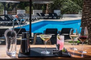 una mesa con copas de vino en una mesa cerca de una piscina en Sunlight Elounda - Adults only Hotel "by Checkin", en Agios Nikolaos