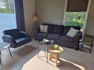 sala de estar con sofá azul y 2 sillas en De Varkensstal, en De Heurne