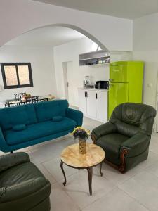 a living room with two blue couches and a table at Charmante villa avec piscine, 3 chambres, salon, cuisine séparée! in Gandigal