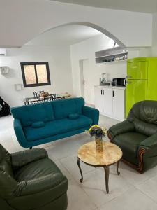 a living room with a blue couch and a table at Charmante villa avec piscine, 3 chambres, salon, cuisine séparée! in Gandigal +4 photos