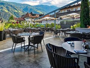 ein Restaurant mit Tischen, Stühlen und Bergen im Hintergrund in der Unterkunft Hotel Panorama in Rabland