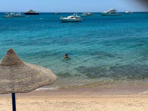 a person in the water on a beach with boats at RITA HOUSE SEA VIEW. Hurghada center in Hurghada
