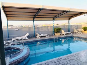 Le Paradise Palace Hotel في دبي: مسبح مع مظلة وكراسي كبيرة
