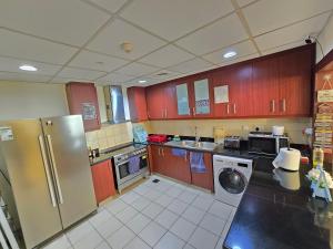 a kitchen with a refrigerator and a washer and dryer at 1 WORLD, Premium Hostel, JBR, Near Metro and Beach in Dubai