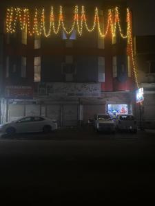Safari Hotel في Dera Ghāzi Khān: مبنى فيه سيارات تقف امامه ليلا
