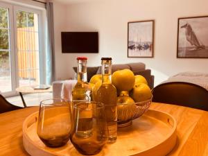 zwei Flaschen und Gläser auf einem Tisch mit einer Schale Zitronen in der Unterkunft Sommerhaus 54, Gartenhaus "S" in Grödersby
