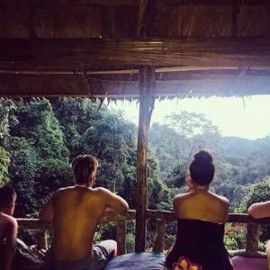 a group of people sitting on a porch looking at the forest at LOVELY JUNGLE LODGE & JUNGLE TREKING only book with us in Bukit Lawang