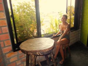 una mujer sentada junto a una mesa y una ventana en Hospedaje Neydita, en Iquitos