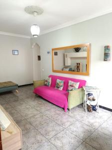 a living room with a pink couch and a mirror at Rincón Mirador Risco Verde in Arinaga +36 photos