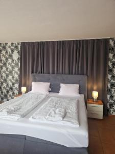 a bedroom with a large white bed with two lamps at Penzion Relax Martina in České Budějovice