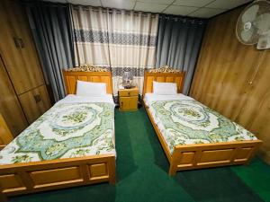 two beds sitting next to each other in a room at Blue Sky Hotel & Restaurant in Skardu