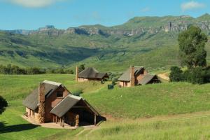 a group of houses in a field with mountains in the background at Top Lodge 4x4 Required in Bonjaneni