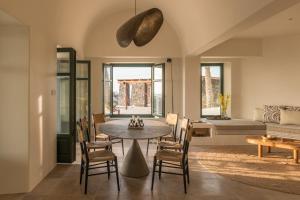 uma sala de estar com uma mesa e cadeiras e um sofá em Patina Vivera Estate Santorini em Pirgos
