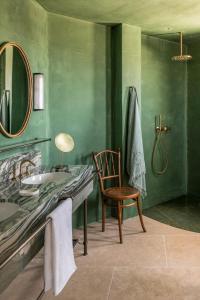 a green bathroom with a sink and a chair at Patina Vivera Estate Santorini in Pyrgos