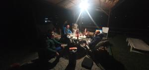 un grupo de personas sentadas alrededor de una mesa por la noche en AUTO KAMP DRINA, en Crnča